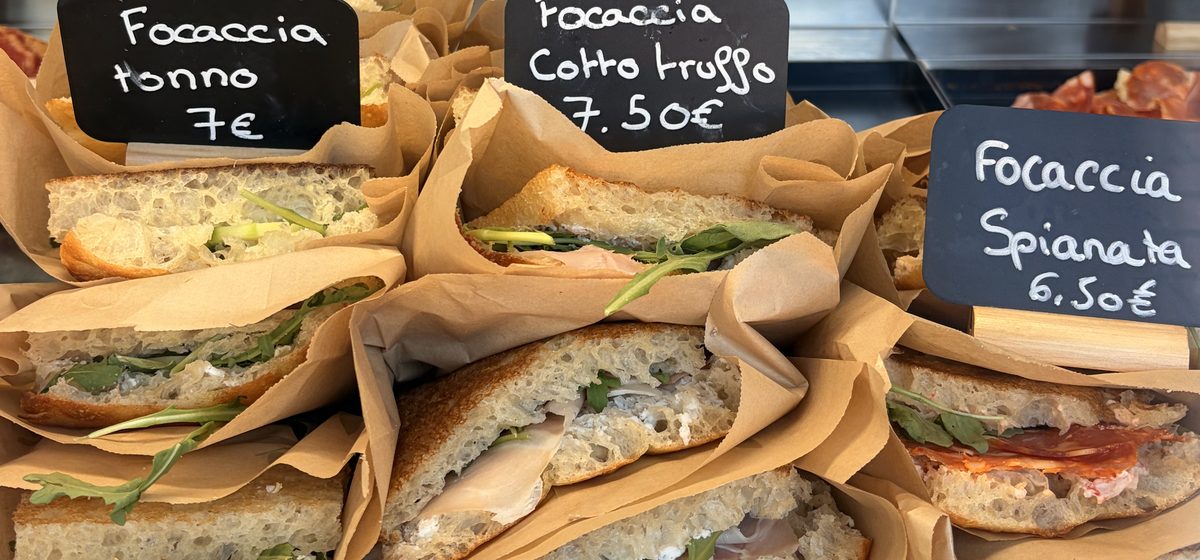 Focaccias garnies emballées en vitrine, avec les ardoises de prix
